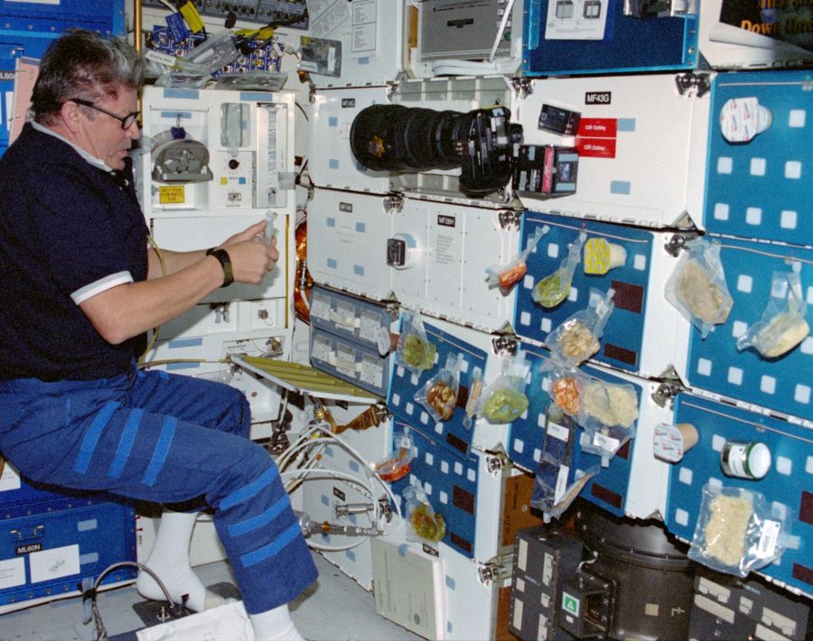 Le cosmonaute Valery V. Ryumin, spécialiste de mission représentant l'Agence spatiale russe (RSA), organise un repas sur le pont intermédiaire de la navette spatiale Discovery en orbite autour de la Terre.