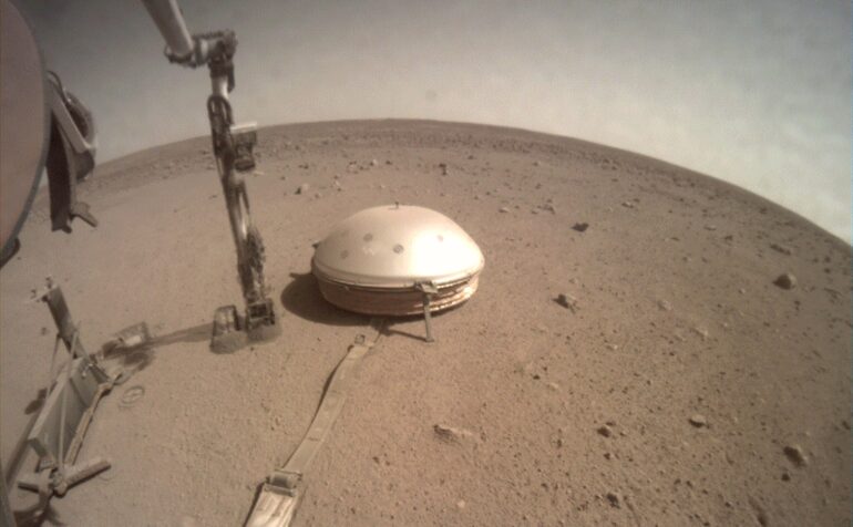 Photographie du sismomètre SEIS. Il a été posé au sol par le bras robotique de l’atterrisseur InSight (immobile, ce n’est pas un rover). Crédit : NASA/JPL-Caltech